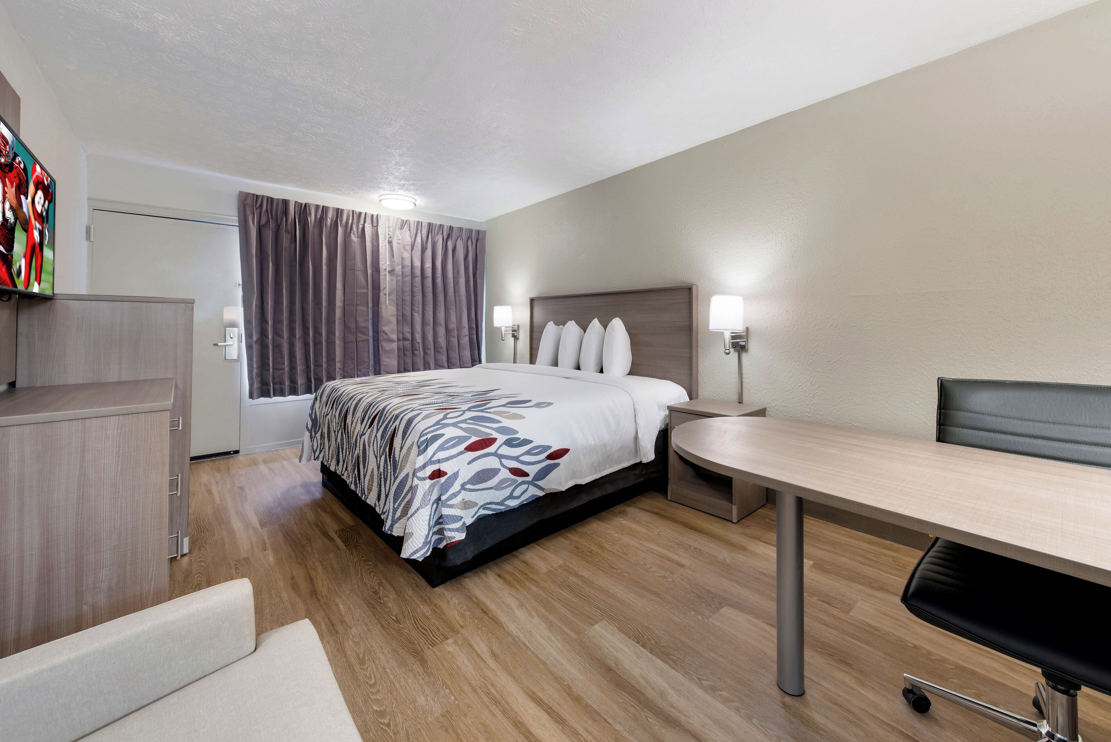A hotel room with a bed, bedside tables, a desk, and a chair.