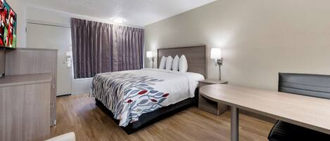 A hotel room with a bed, bedside tables, a desk, and a chair.