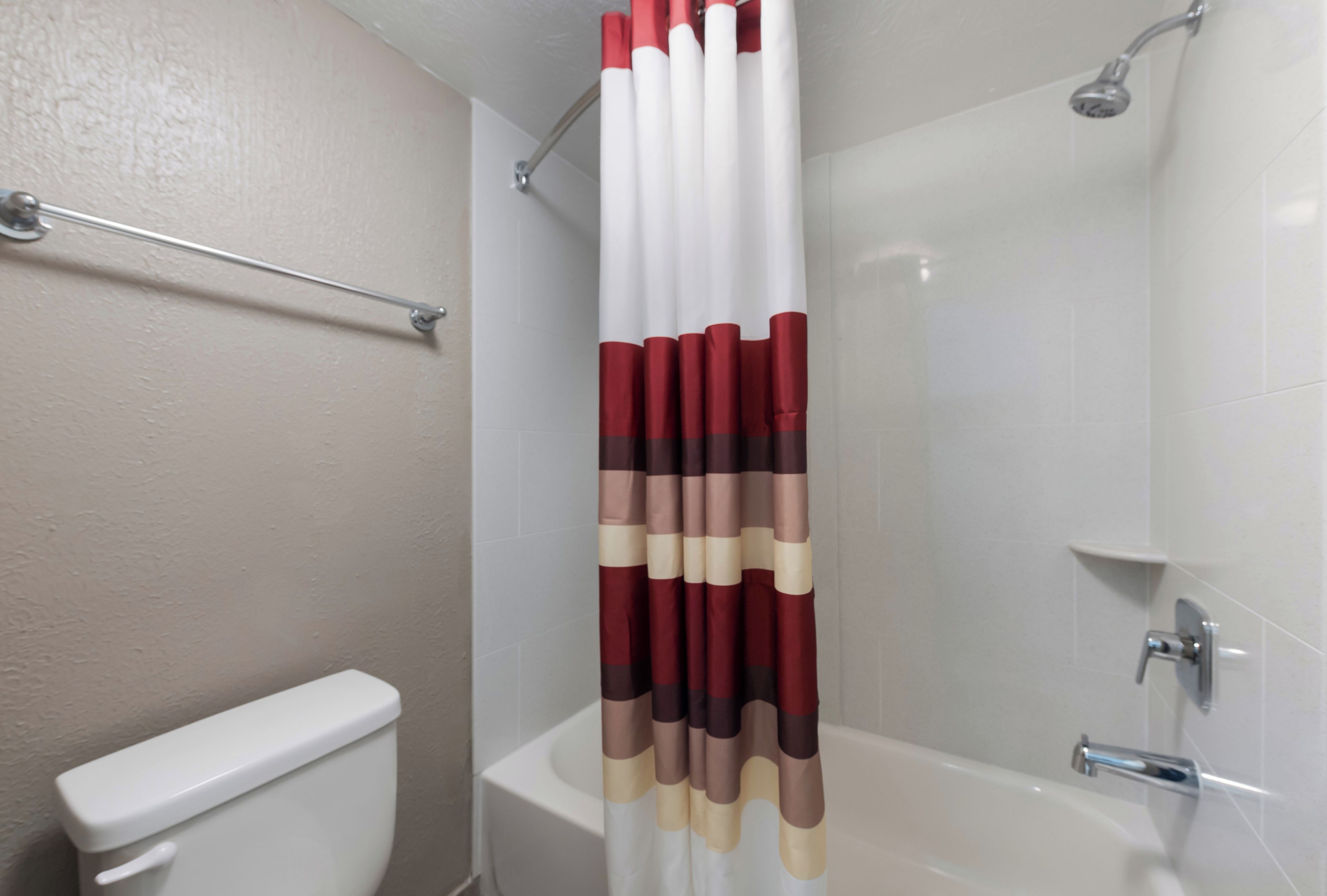 Un baño con una bañera blanca, un inodoro y una cortina de ducha a rayas.