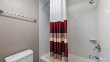 A bathroom with a white bathtub, a toilet, and a shower curtain with a striped pattern.