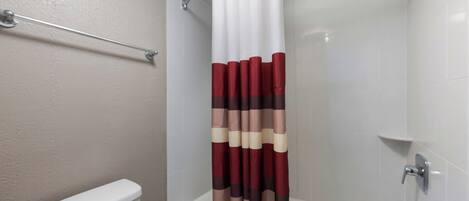 Un baño con una bañera blanca, un inodoro y una cortina de ducha a rayas.