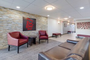 A lobby with stone walls, a Red Roof Inn sign, leather seating, and a tiled floor. - Red Roof Inn Dayton - Moraine/U of Dayton (Moraine)