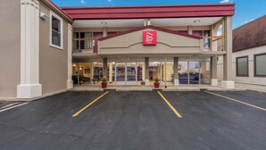 Red Roof Inn -niminen majoitusliike, jossa on kaksikerroksinen rakennus, punainen katto ja merkityillä paikoilla varustettu pysäköintialue.