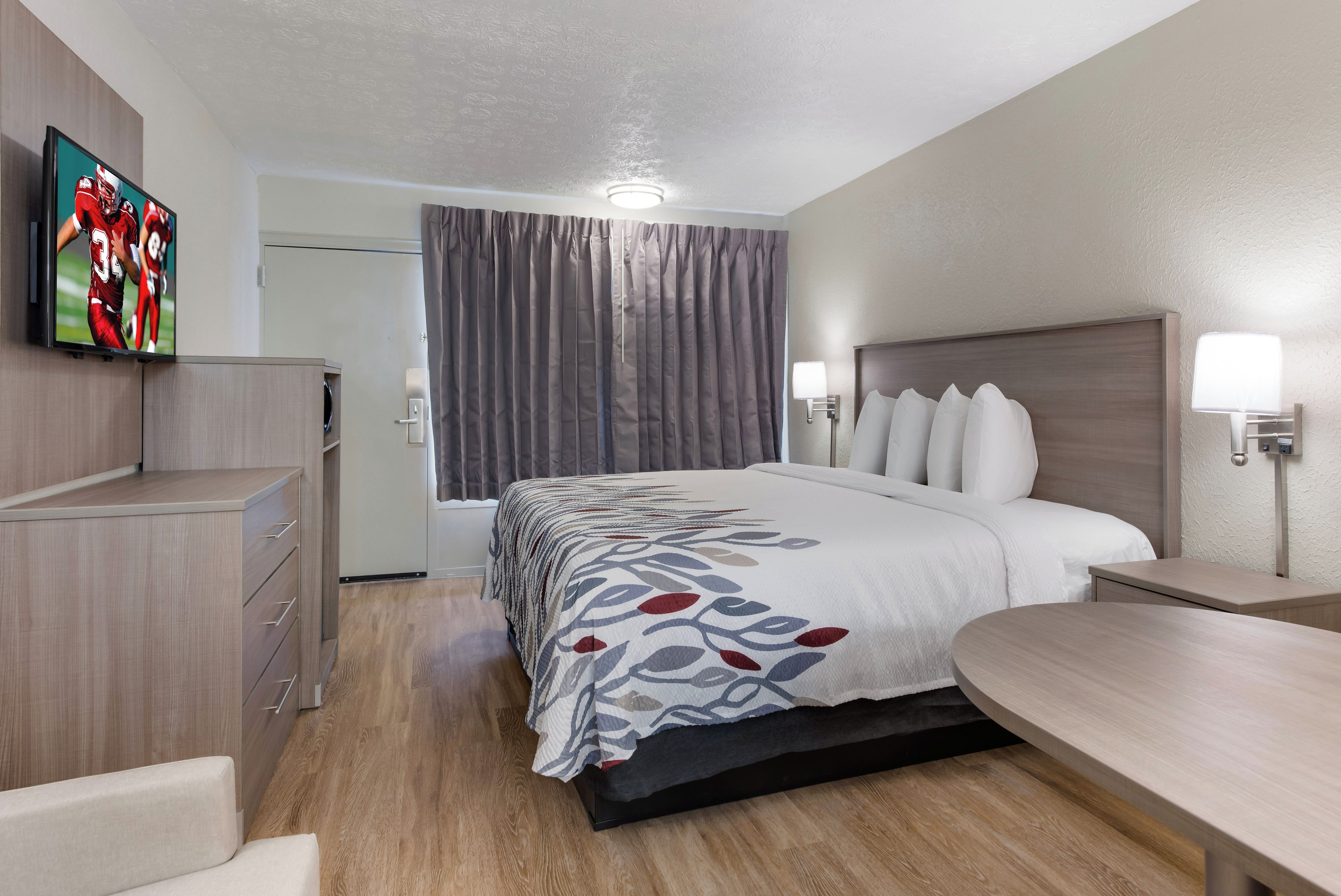 Una habitación de hotel con cama, mesitas de noche, escritorio, televisión y armario.