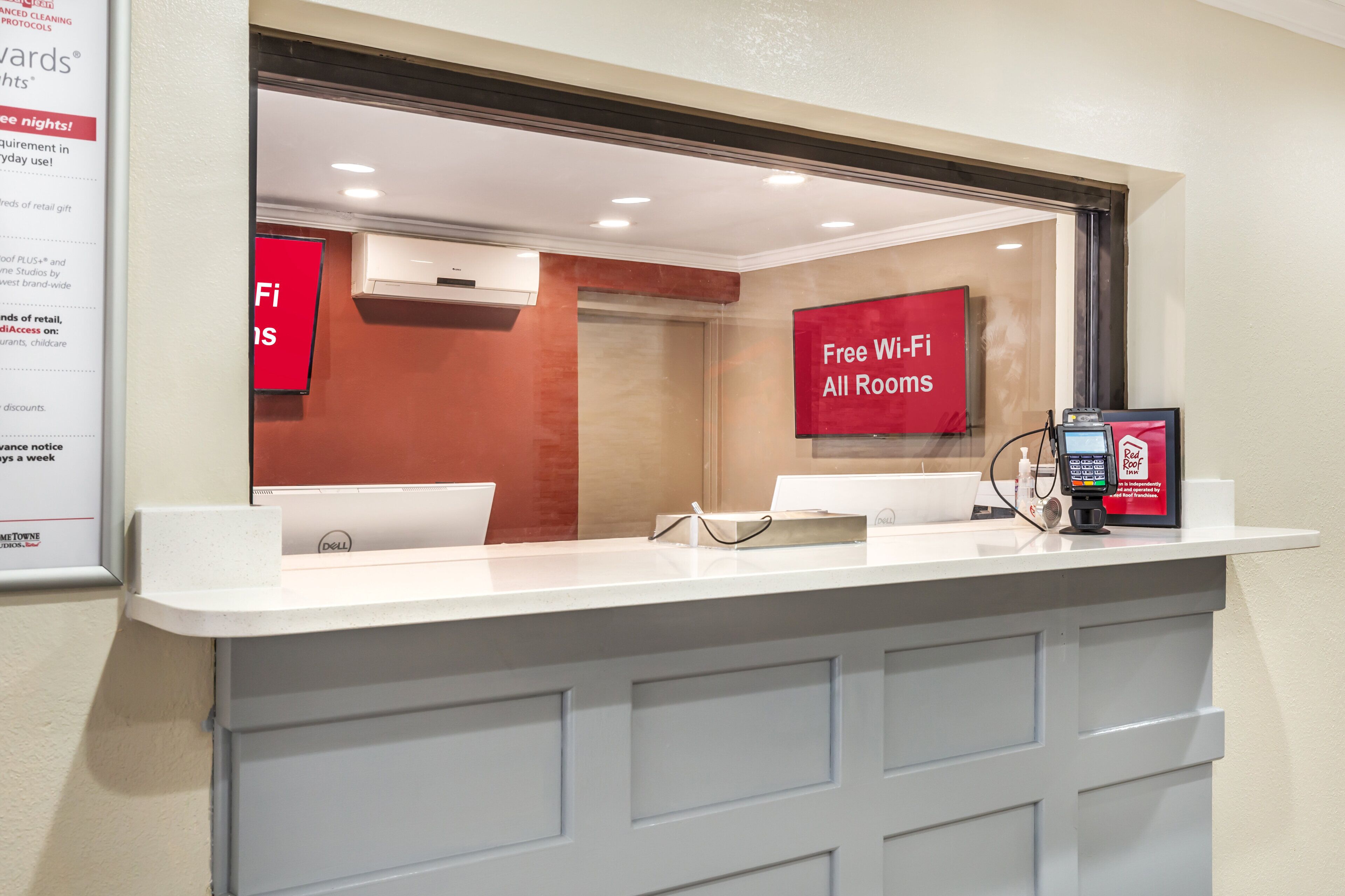 Un espace d’accueil d’hôtel avec un comptoir, une enseigne Red Roof Inn et un ordinateur Dell.