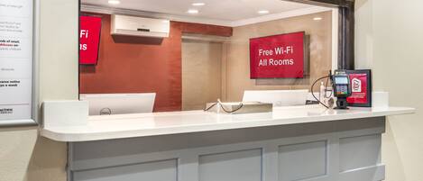 A hotel reception area with a counter, a Red Roof Inn sign, and a Dell computer.