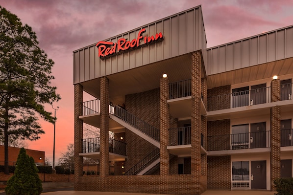 Ein Red Roof Inn mit Ziegelverkleidung, mehreren Balkonen und einer auffälligen Beschilderung.
