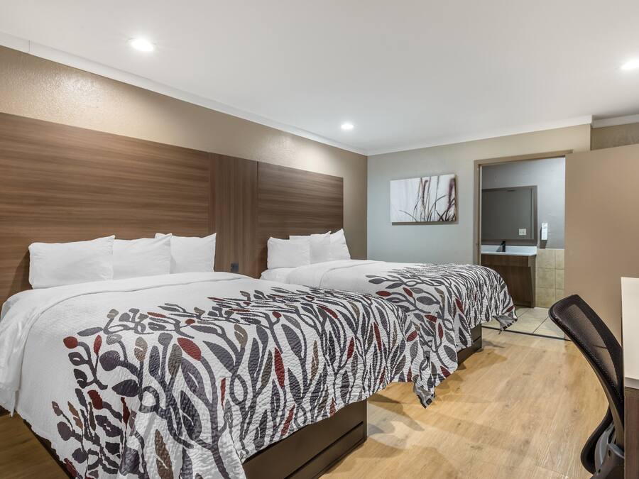 Quarto de hotel com uma cama grande, uma escrivaninha e um espelho.