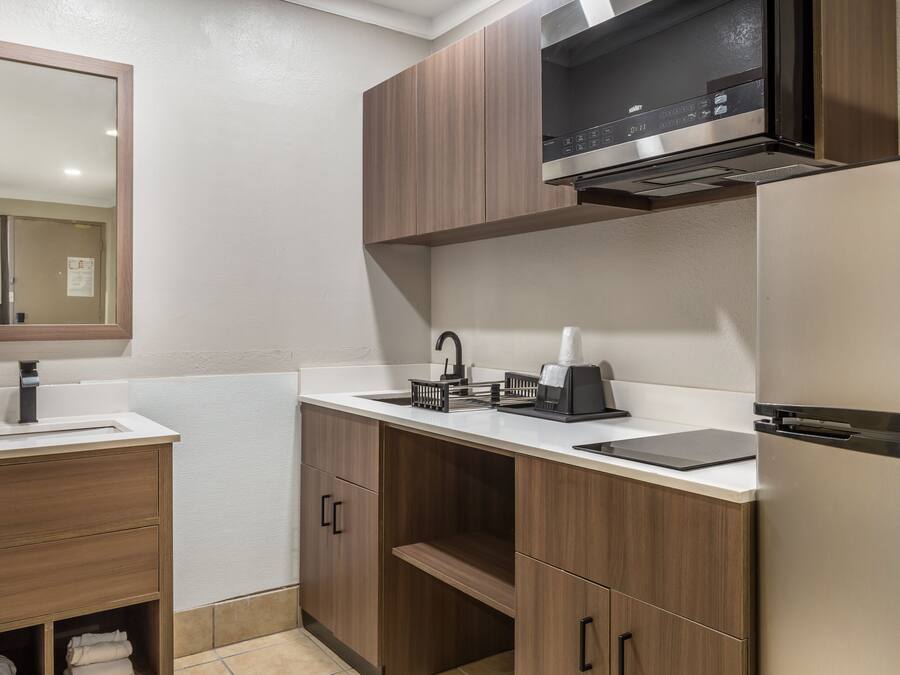 A modern bathroom with a sink, mirror, cabinet, and a built-in microwave.