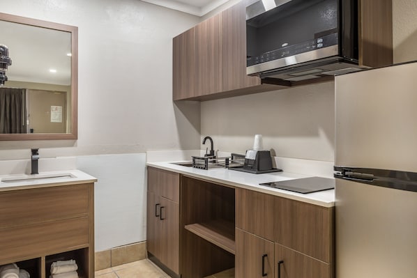 A modern bathroom with a sink, mirror, cabinet, and a built-in microwave. - Red Roof Inn Raleigh Northeast - Downtown (Raleigh)