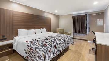 Una habitación de hotel con una cama grande, un escritorio, una silla y una puerta corrediza.