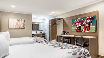 A hotel room with two beds, a desk, a television, and a mirror.
