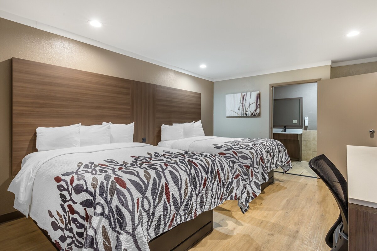 Ein Hotelzimmer mit einem großen Bett, einem Schreibtisch und einem Spiegel.