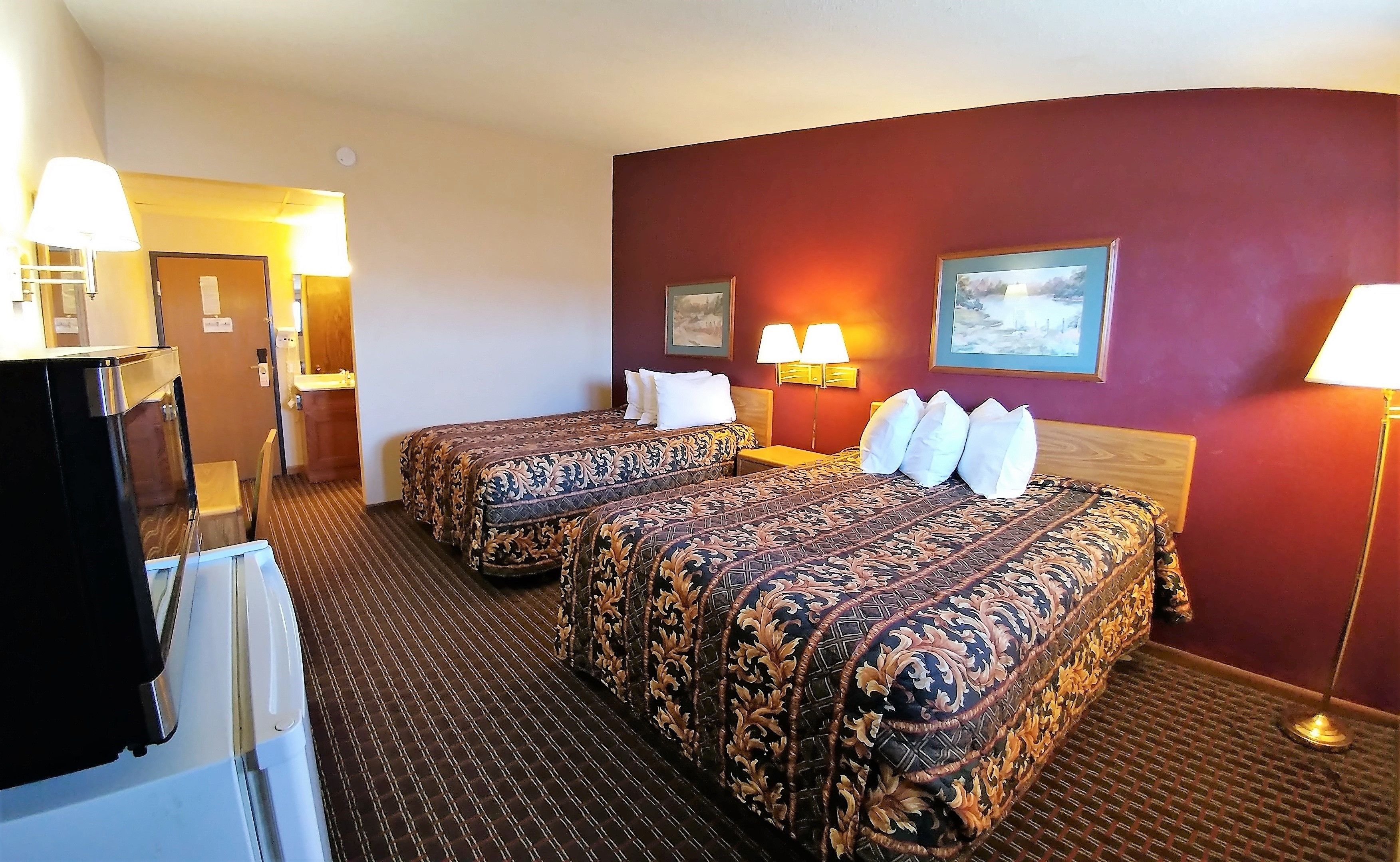 A hotel room with two beds, a desk, and a bathroom.