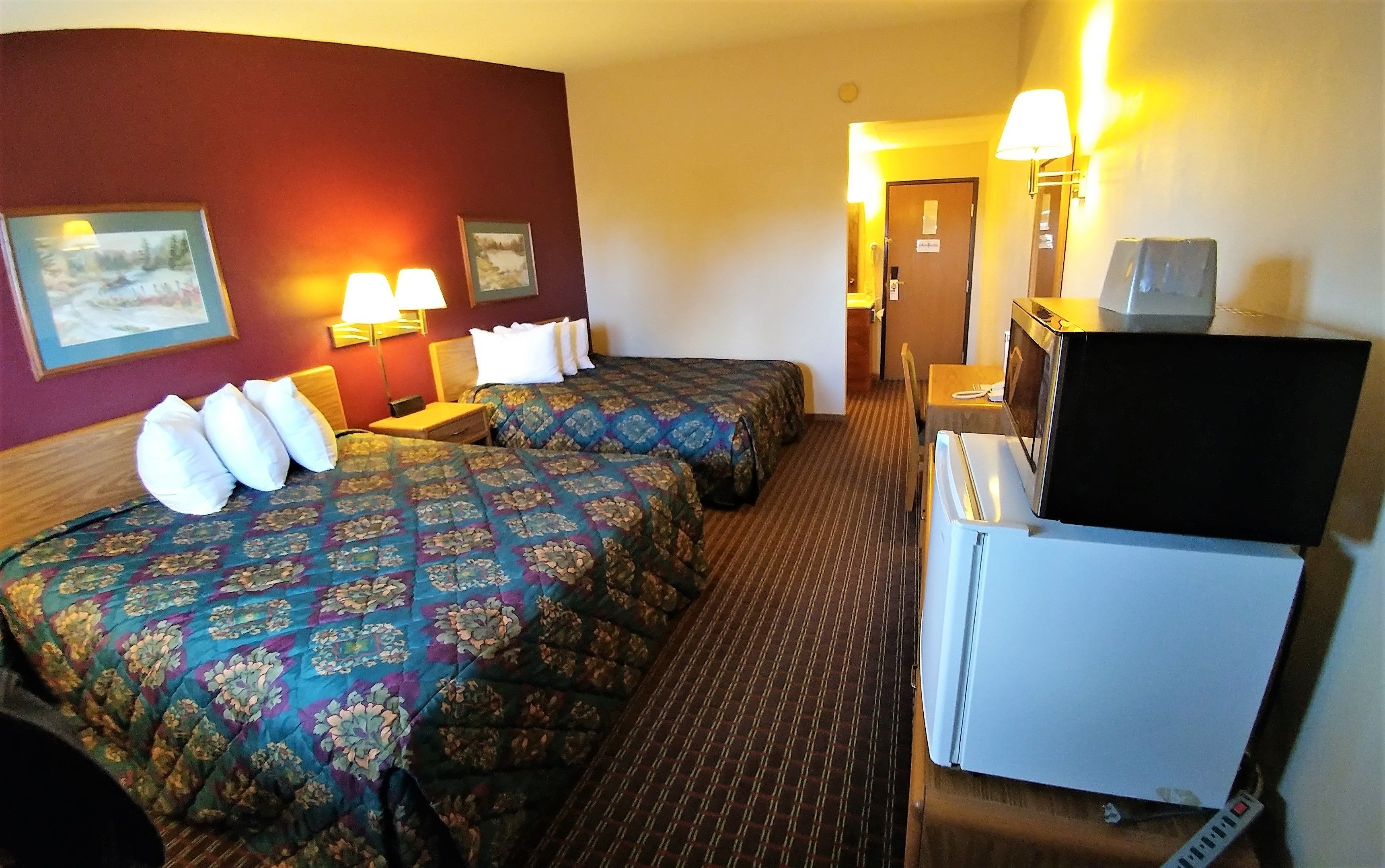 A hotel room with two beds, a television, a desk, and a chair.