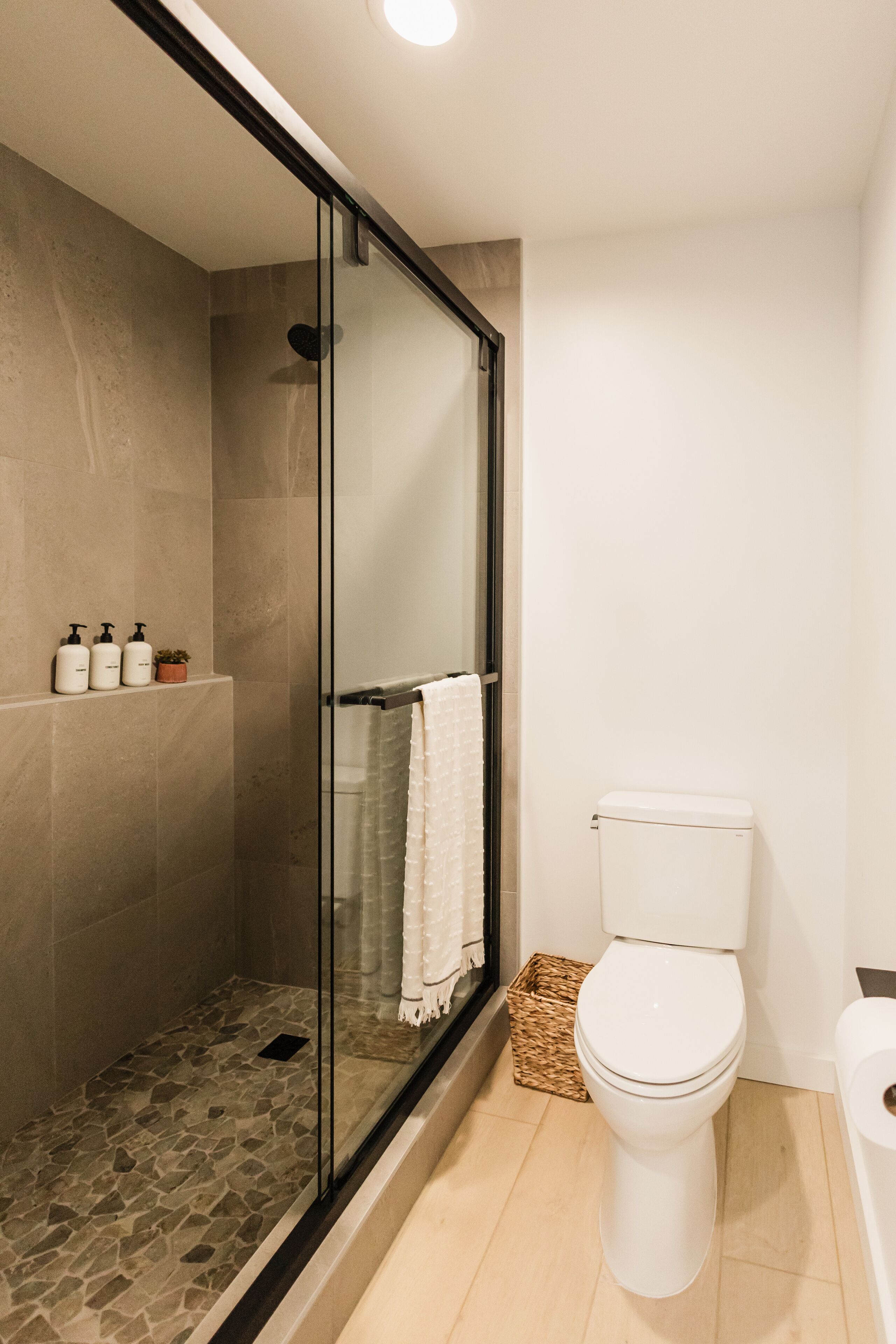 A modern bathroom with a glass-enclosed shower, a toilet, and a bathtub.