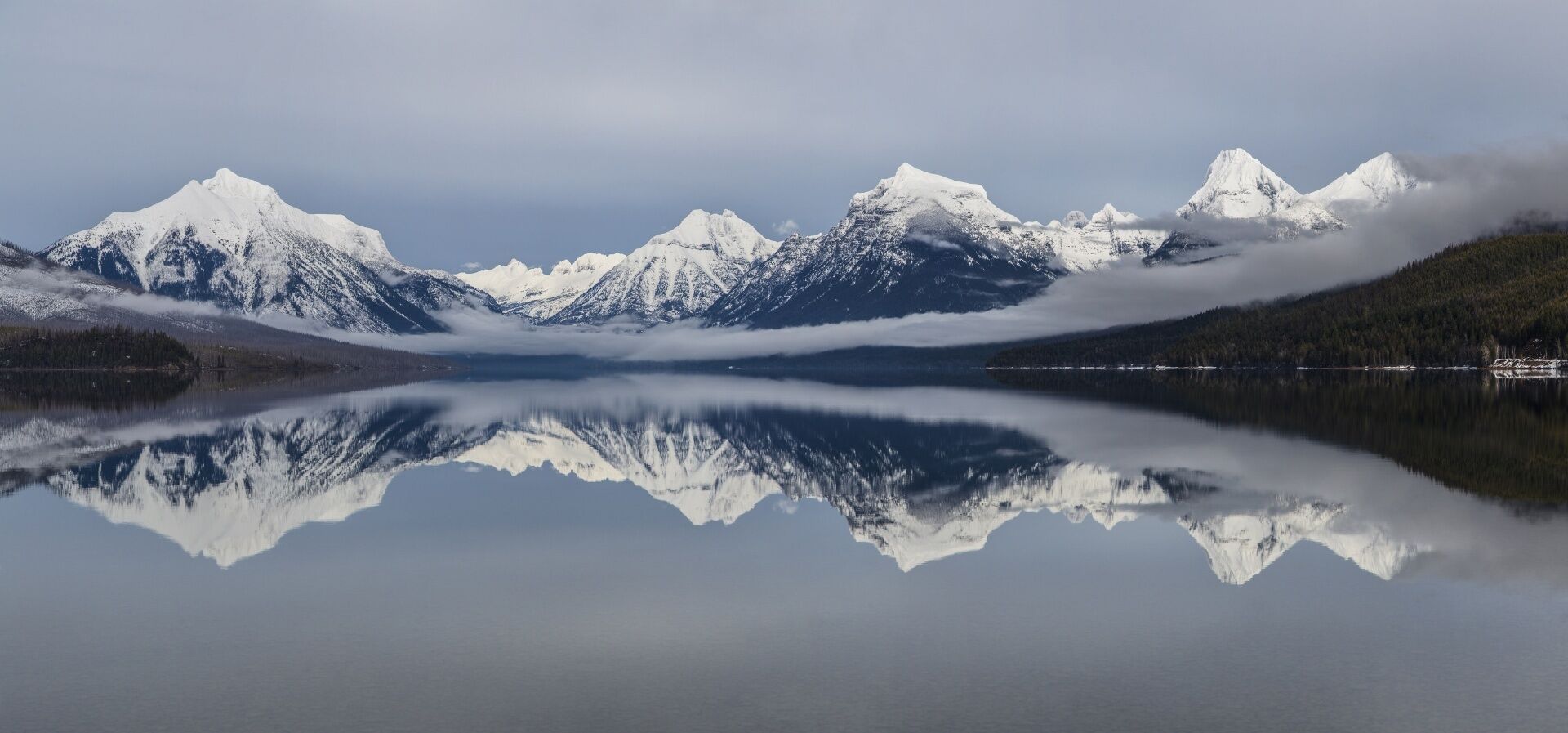 Un lac paisible dont les eaux reflètent les montagnes enneigées qui l’entourent.