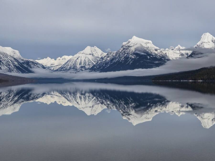 A tranquil lake with snow-capped mountains reflected in the water.