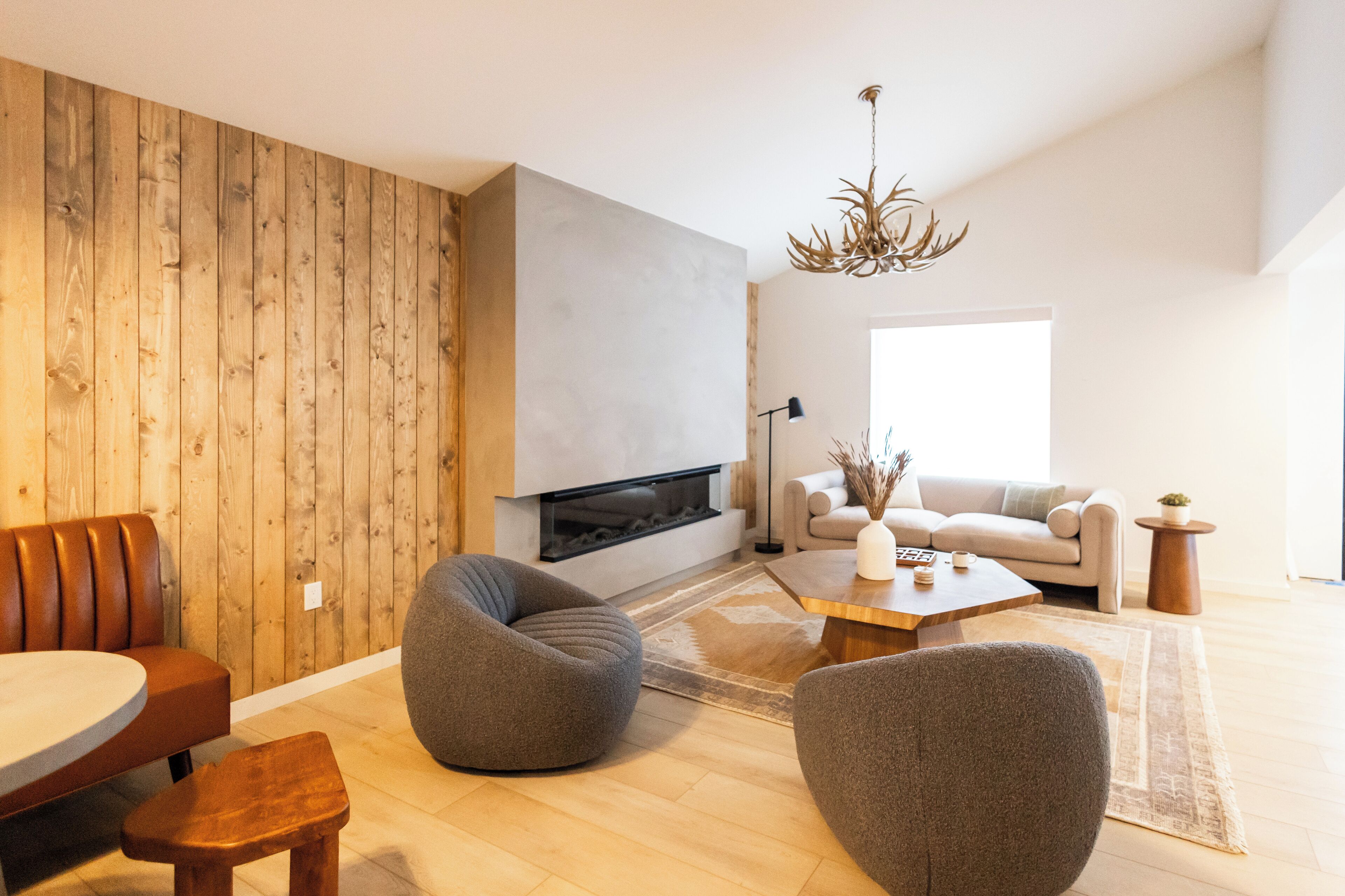 Una sala de estar moderna con chimenea, paneles de madera y mobiliario contemporáneo.