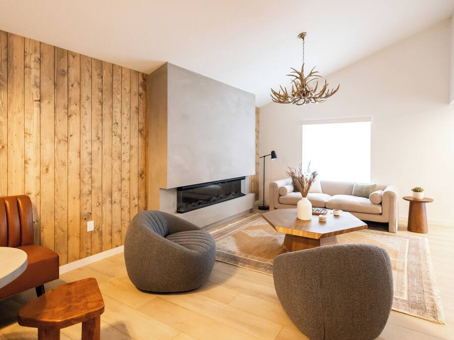 Una sala de estar moderna con chimenea, paneles de madera y mobiliario contemporáneo.