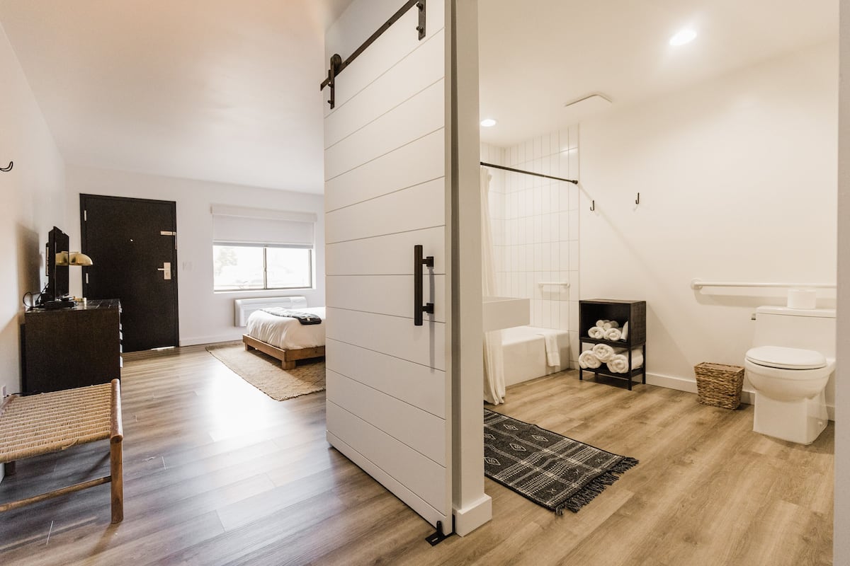 A modern bathroom with a shower, toilet, and a small shelf with towels.