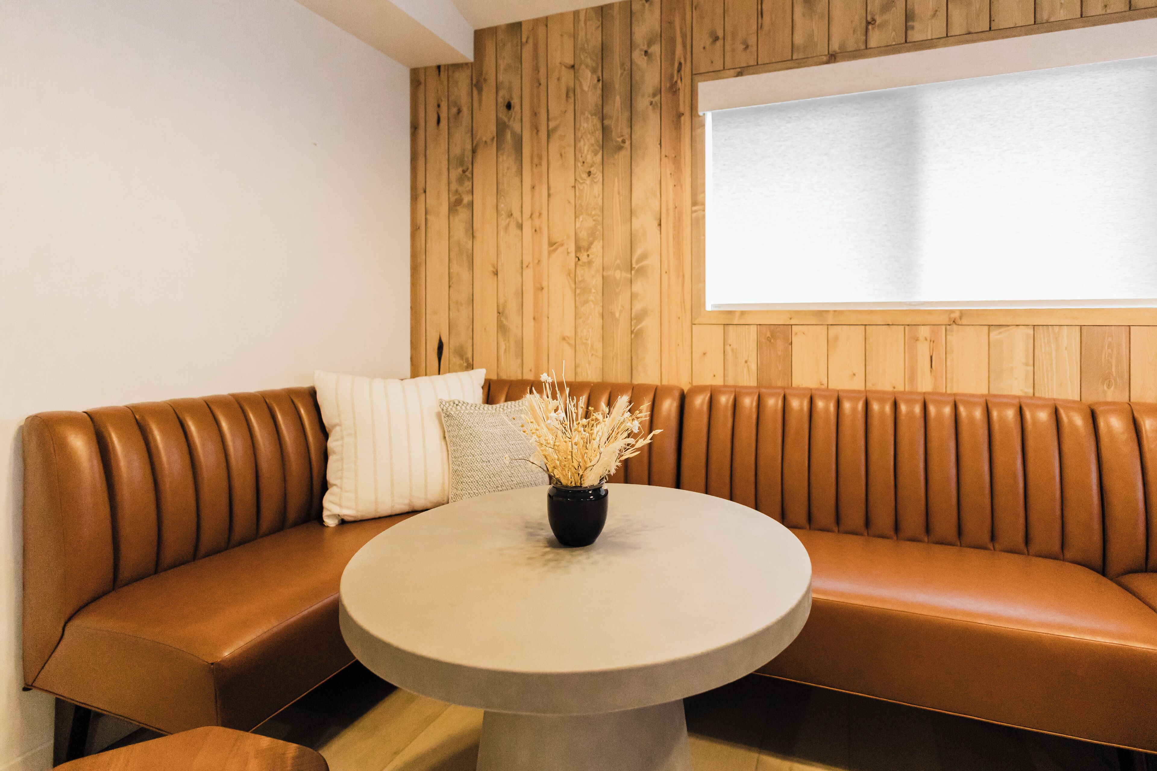 A modern room with a brown leather sofa, a round table, and a wooden wall panel.