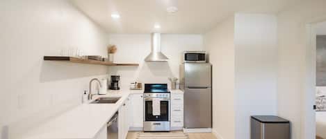 A modern kitchen with white cabinetry, a stainless steel oven, a microwave, and a refrigerator.