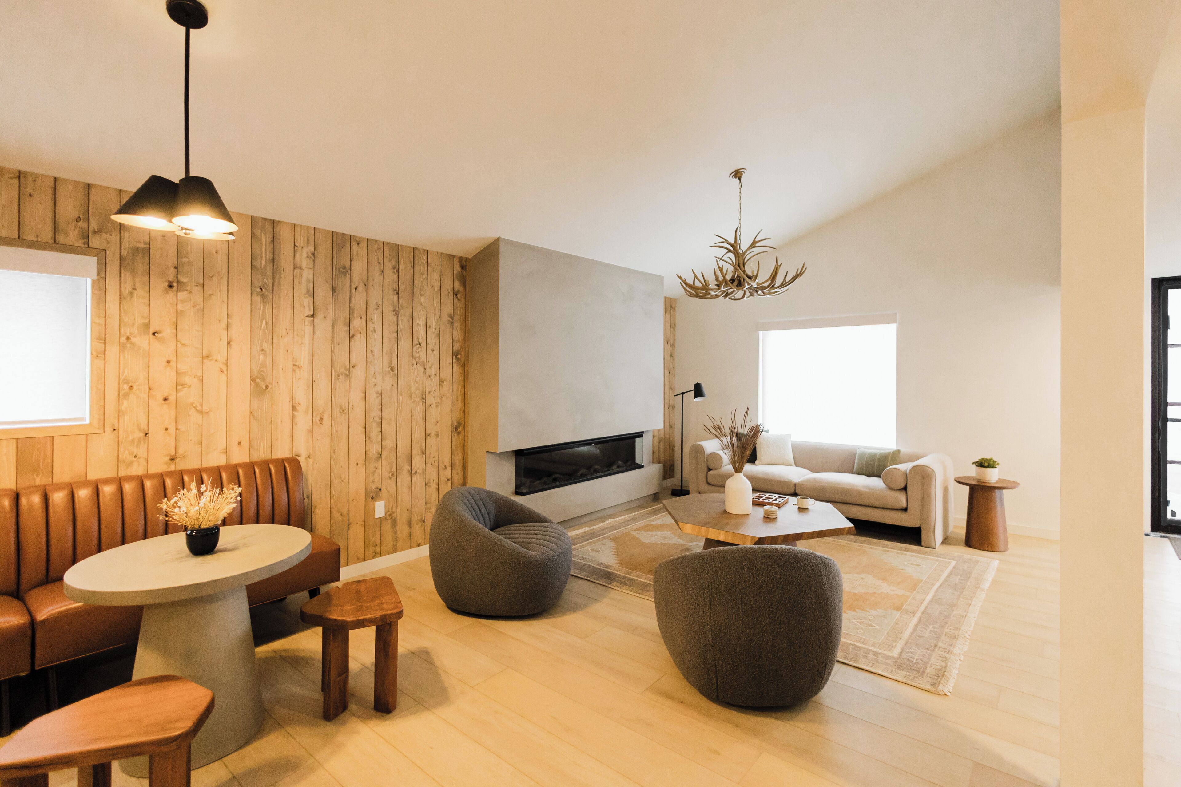 A modern living room with a fireplace, wooden panel walls, a round coffee table, and a sofa.