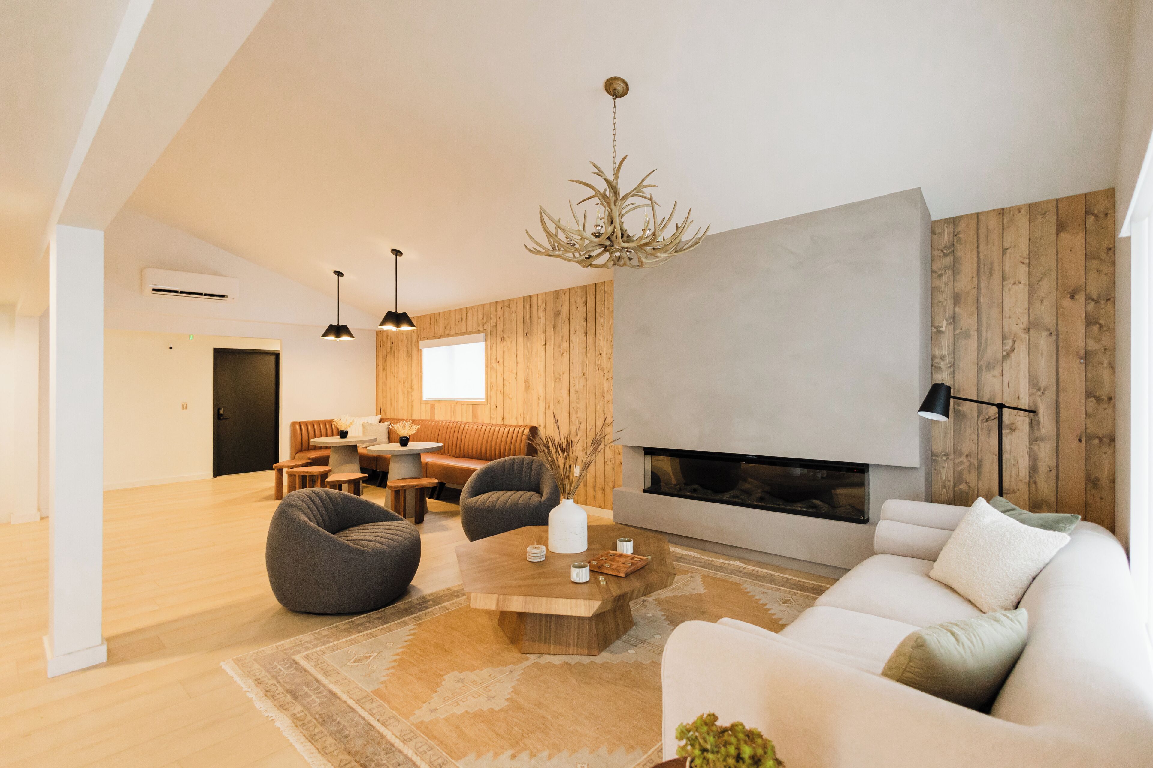 Una sala de estar moderna con chimenea, paredes de madera y un ventanal grande.