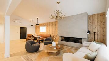 Una sala de estar moderna con chimenea, paredes de madera y un ventanal grande.