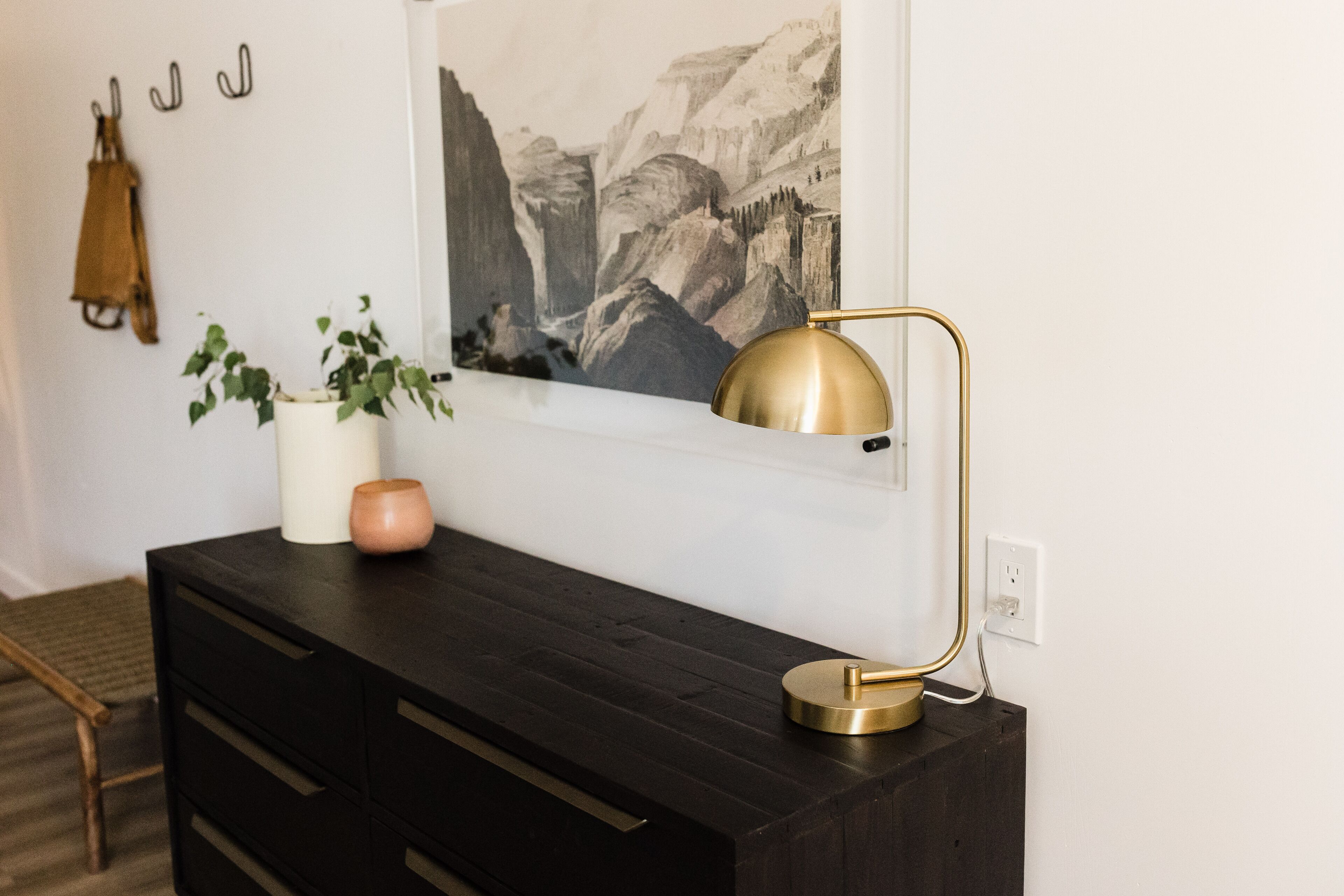 A dark wooden desk with a gold lamp, a potted plant, and a vase.