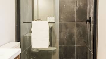 A modern bathroom with a glass-enclosed shower, a white toilet, and a tiled floor.