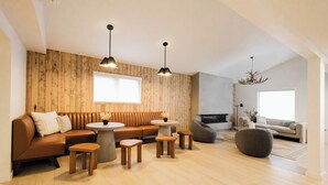Una sala de estar moderna con una pared de madera, sofá de cuero, mesas redondas y una chimenea.