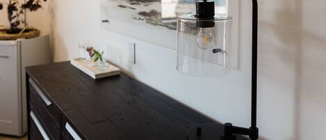 A modern room with a dark wooden dresser, a clear glass bottle with a pump, and a framed artwork on the wall.