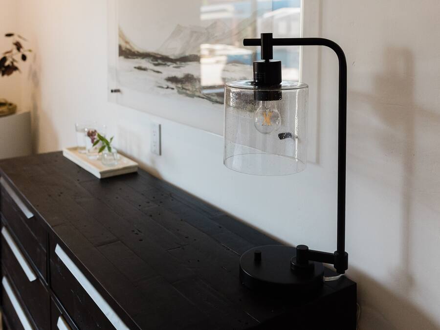Ein modernes Zimmer mit einem dunklen Holzkasten, einer klaren Glasflasche mit Pumpe und einem gerahmten Kunstwerk an der Wand.
