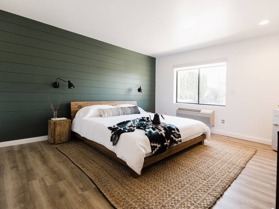 A bedroom with a bed, bedside lamps, a window, and a radiator.