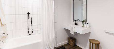 Un baño con bañera, ducha, lavabo y espejo.