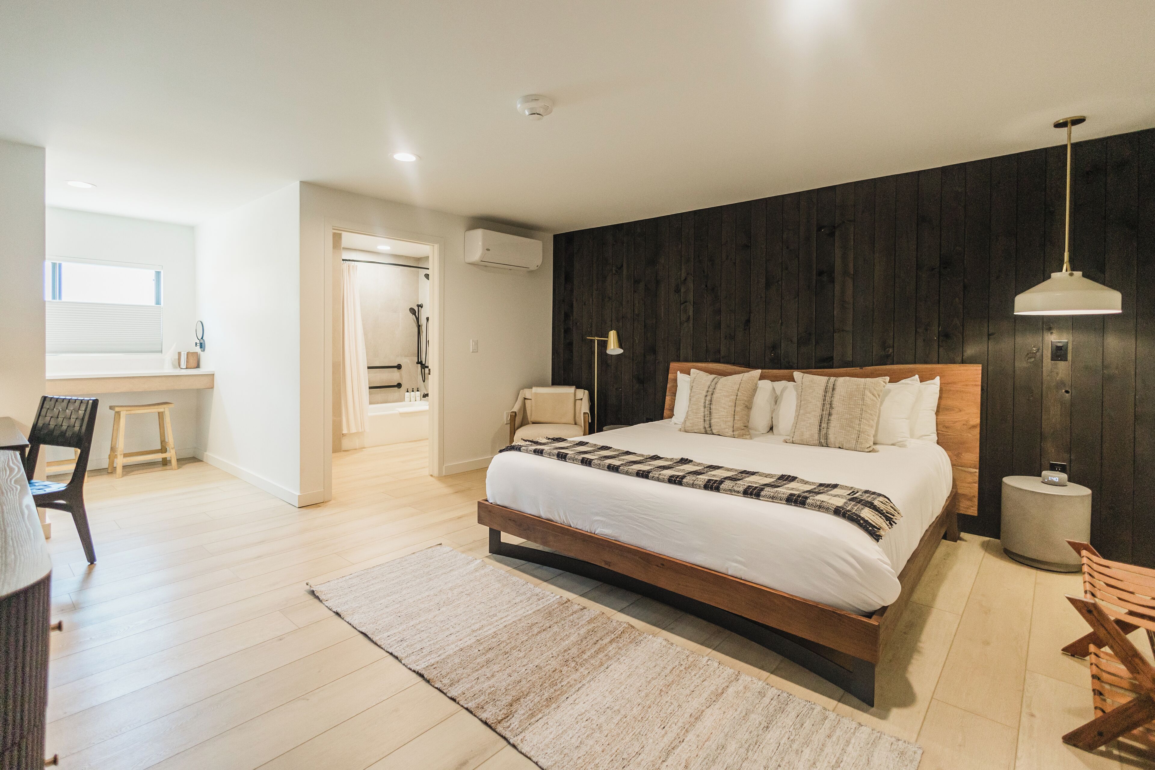 Une chambre moderne avec un lit en bois, une lampe de chevet et une grande fenêtre.