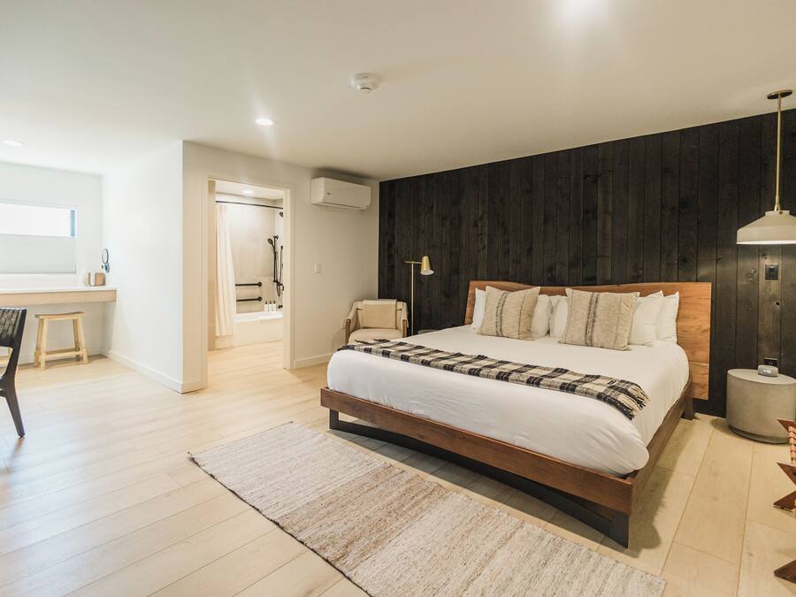 Une chambre moderne avec un lit en bois, une lampe de chevet et une grande fenêtre.