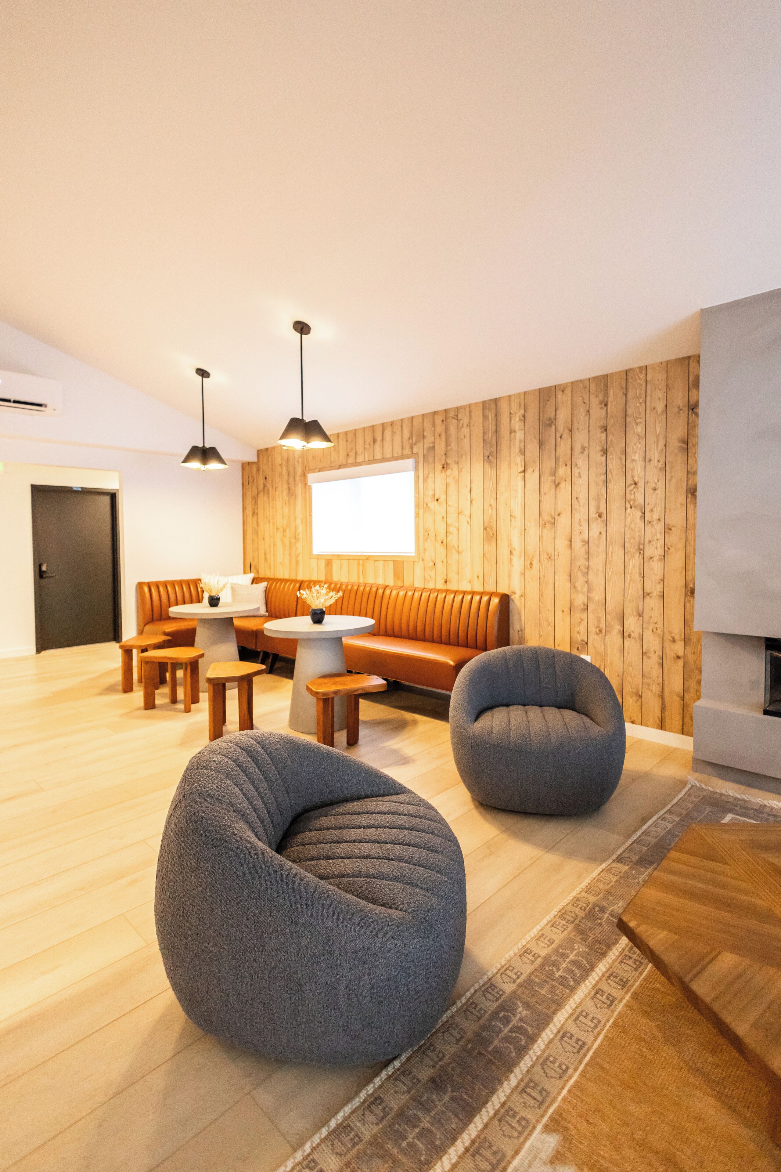 A modern living room with a wooden wall, a sofa, two bean bags, a coffee table, and a fireplace.