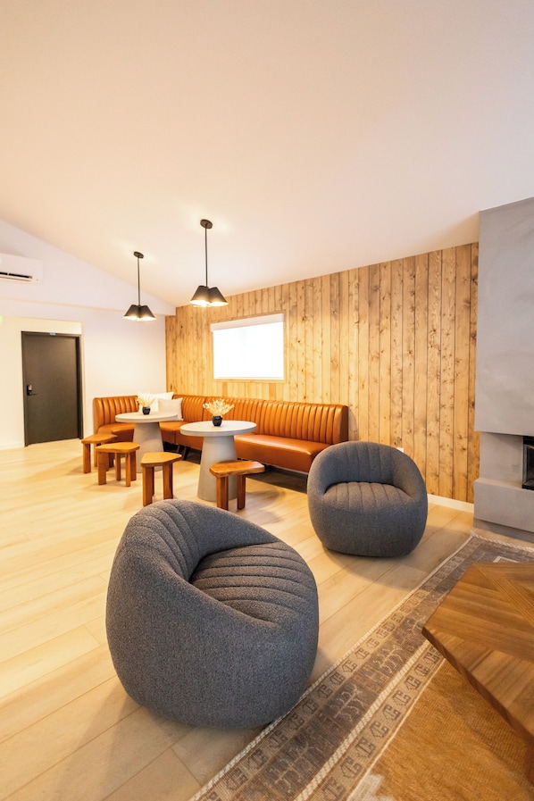 Una sala de estar moderna con una pared de madera, un sofá, dos sillones tipo orejero y una chimenea.