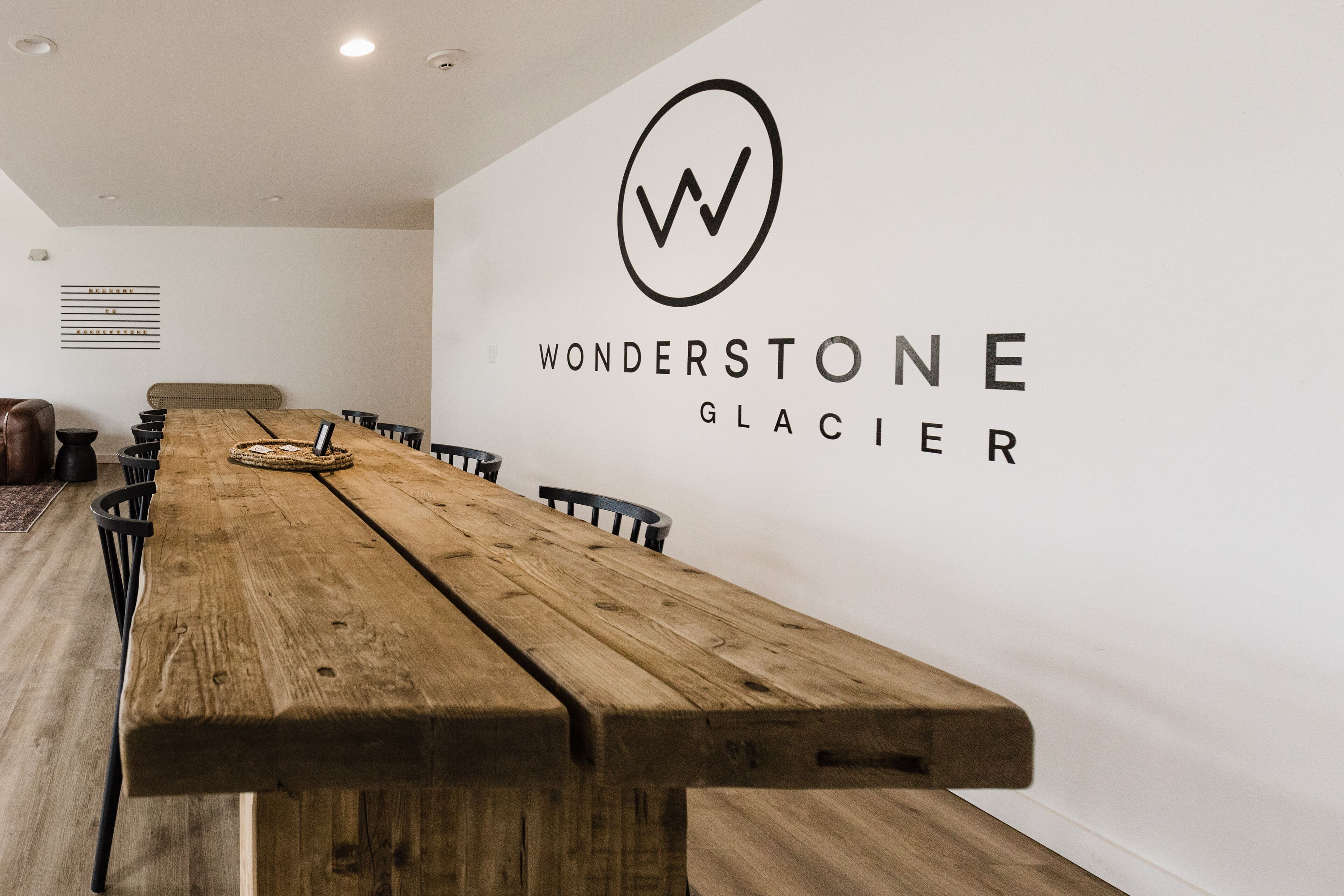 Una larga mesa de madera en una habitación moderna con una pared blanca y un logotipo que dice "WONDERSTONE GLACIER".