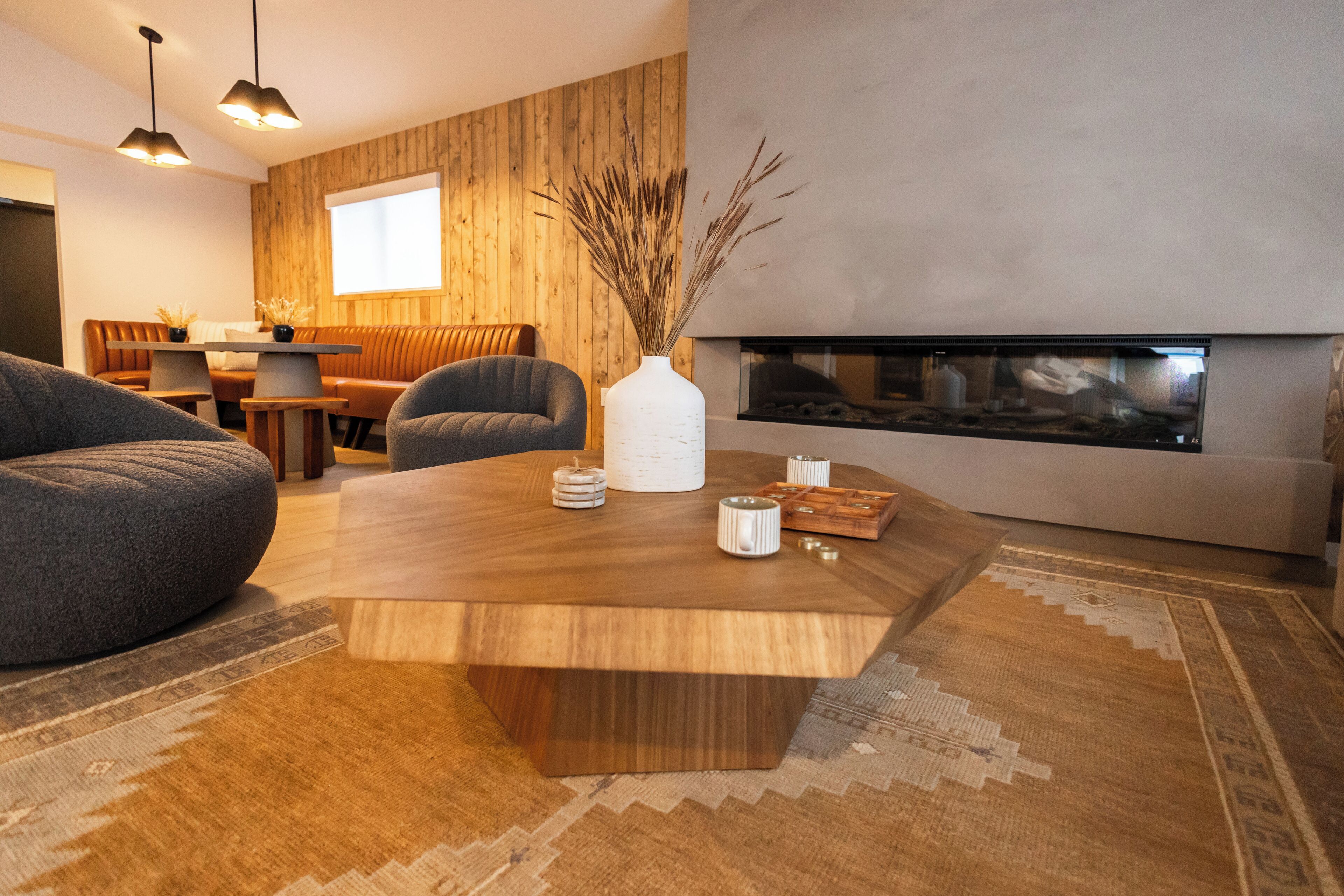 A modern living room with a wooden coffee table, a sofa, and a fireplace.