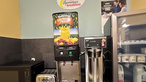 Una barra de desayuno con una máquina de café, un tostador y un refrigerador que contiene cartones de leche.