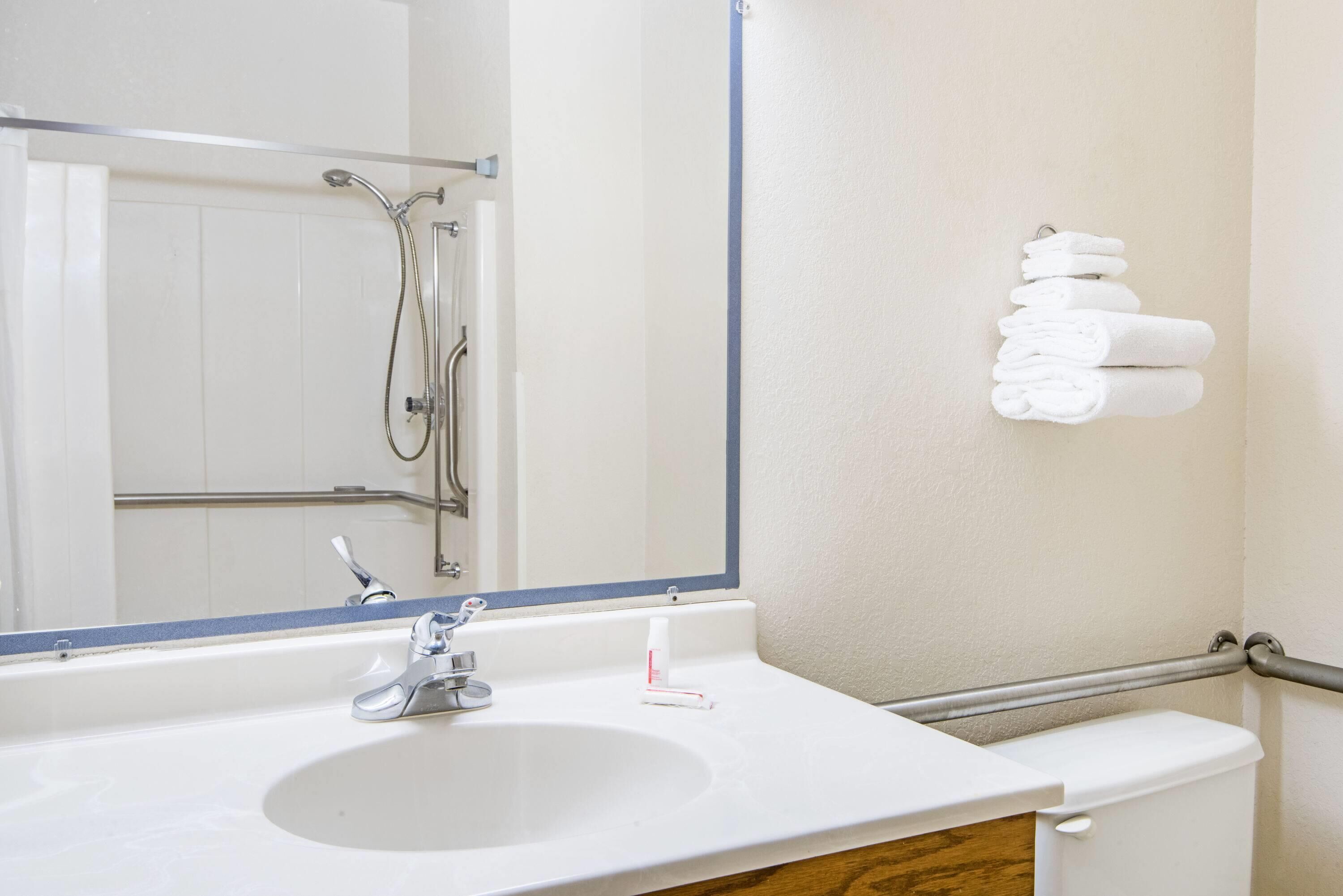 Une salle de bain équipée d’un lavabo, d’un miroir, d’une douche et d’un porte-serviettes.