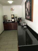 A kitchen area with a microwave, coffee machine, and a coffee station.