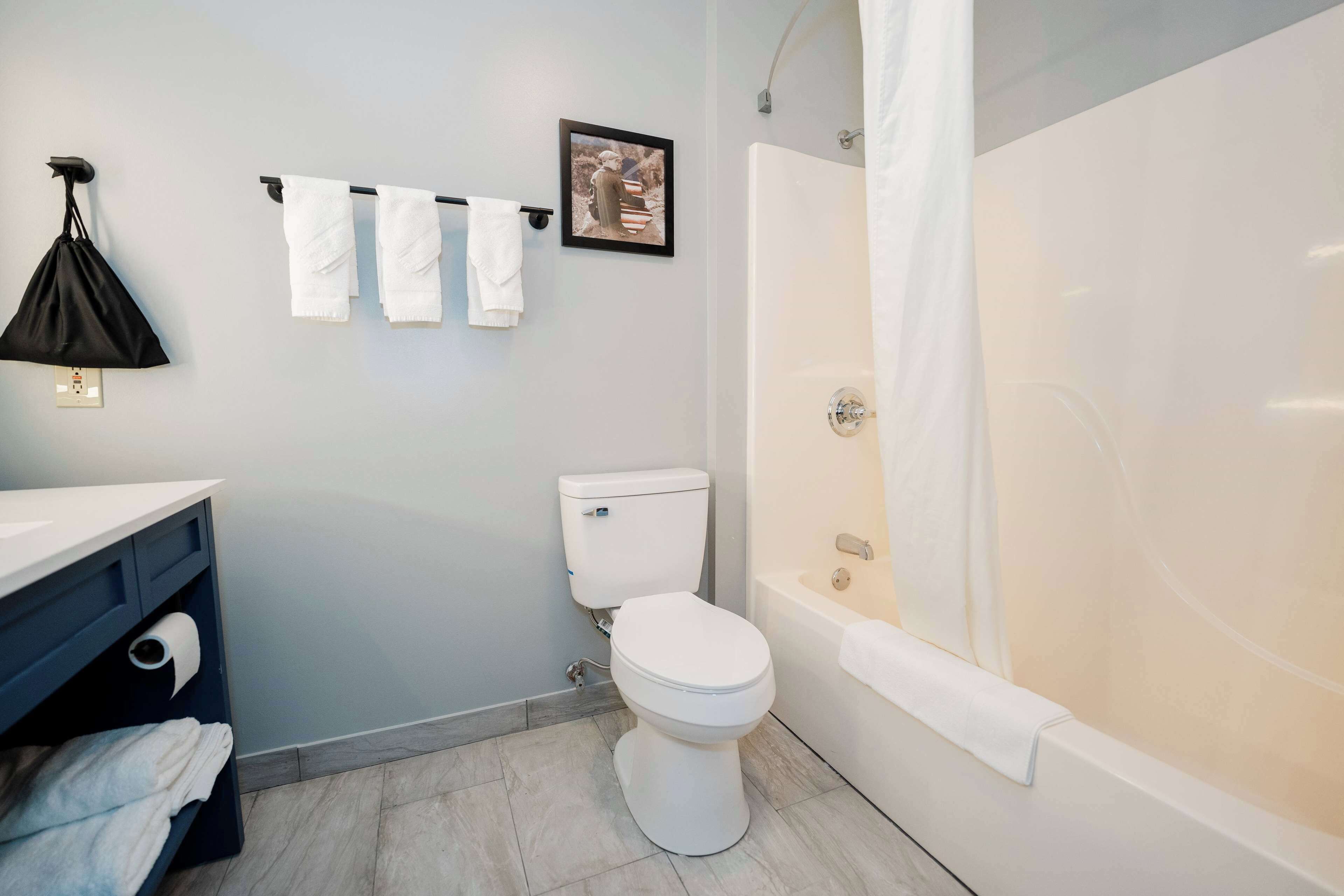 Un baño con inodoro, bañera y toallero con toallas.