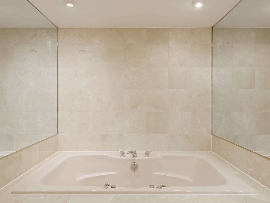 A modern bathroom with a large bathtub, tiled walls, and recessed ceiling lights.