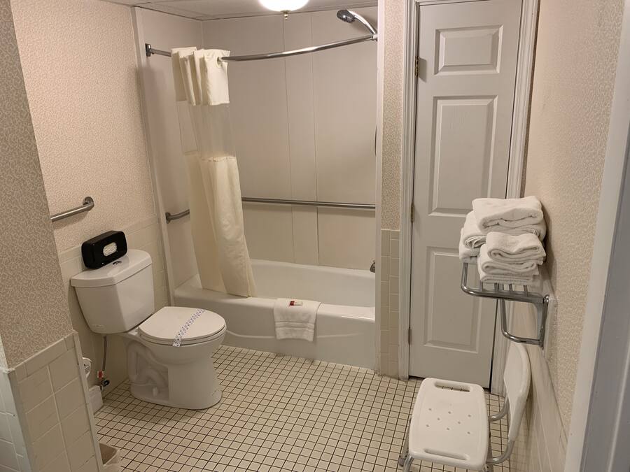 A bathroom with a toilet, a shower with a glass door, a bathtub, and a towel rack with folded towels.