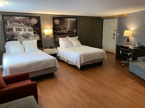 Habitación de hotel con dos camas, un escritorio, una silla y una puerta.